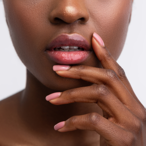 woman with dark skin and plump lips touching mouth area with hand